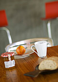 Apfel auf Teller mit Messer Tasse und Marmelade auf Holztischplatte