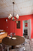 Runder Tisch in rotem Wohnzimmer mit Deckenleuchte