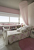 Pink bedroom with patterned wallpaper and patchwork quilt