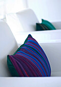 Striped purple blue and green cushion on white armchair