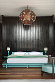 Brass metalworked lampshade in panelled room with painted double bed
