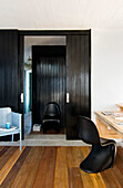 Chair at wooden desk with view through panelled black sliding doors to hallway
