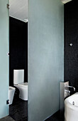 Black tiled bathroom with frosted glass room divider