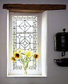 Vase of sunflowers on sunlit windowsill with original beam 