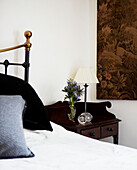 Brass bedhead with dark wood antique bedside table and tapestry wall hanging