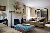 Turquoise ottoman in sunlit 17th Century Oxfordshire living room with cream sofas