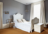 Single bed in light grey bedroom with coir matting