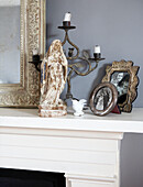 Figurine and silver picture frames on mantlepiece with carved mirror and candlestick holder