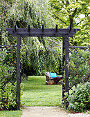 View through wooden archway to outdoor seating in lawned garden