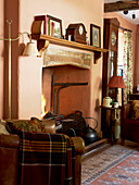 Leather armchair at open fireplace with clock on mantle