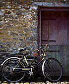 Bicycle leans on wall near stable door