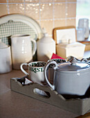 Teekanne und Milchkännchen auf einem Küchentablett