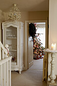 Christmas wreath on open door with painted white glass fronted cabinet