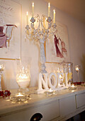 Lit candles and artwork with crystal glassware on painted console table