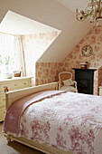 Pink floral patterned bedroom with sunlit dormer window