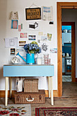 Blue cut flowers on hallway folding table with a collection of postcards