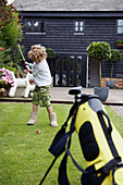 Kleiner Junge spielt Golf im Garten
