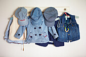 Denim children's clothes and hats hanging on hooks on the wall