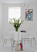 Handbag on chair in all white dining room with artwork of Che