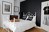 White cast iron bed in room with black feature wall