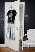 Silver vintage clothing hangs on the back of a bedroom door