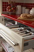 Red kitchen worktop and open cutlery drawer