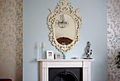 Ornate mirror frame above fireplace with walls papered in Oriental Garden by Laura Ashley