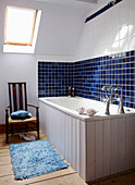 Panelled bathtub in blue tiled Georgian townhouse bathroom with skylight