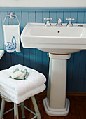 White folded towels with turquoise panelling and pedestal wash basin in bathroom of Wairarapa home North Island New Zealand