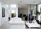 Weißes Sofa im Empfangsraum mit Schiebetüren, die zum privaten Wohnzimmer führen