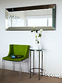 Lindgrüner Stuhl und metallgerahmter Beistelltisch unter dem Spiegel
