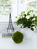Geschnittene Rosen und Modell des Eiffelturms auf Schreibtischplatte im Fenster