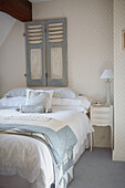 Pastel blue bed covers on double bed with salvaged shutters