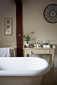 Rolltop bath and painted side table with toiletries and clock