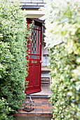 Red stained glass front door opening from garden path 