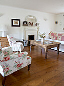 Sessel mit Blumenmuster und restauriertem Tisch im Wohnzimmer eines Landhauses