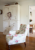 Floral patterned armchair with salvaged cupboard unit in country house