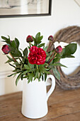 Jug of cut flowers on country house sideboard