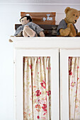Teddy bears and suitcases on top of painted wardrobe