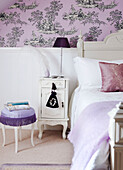 Bedroom detail with patterned wallpaper and painted bedside cabinet