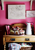 Knitted teacakes and teacosy on sideboard in pink room with artwork