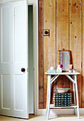 Side table with panelled wood wall and open bathroom door