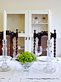 Glassware on table with wooden chair backs and painted cabinet