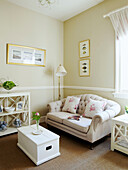 Floral cushions on cream sofa with white painted box and shelving