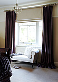 Violette Vorhänge und Chaiselongue am Fenster