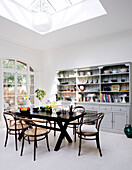 Kitchen dresser with table and chairs under sunlit skylight