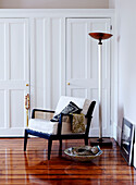 Armchair on polished wooden floor of London bedroom with walk-in wardrobe