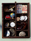 Wooden box with compartments displaying vintage memorabilia including clocks fossils and cigarette boxes