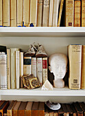Shoes on books with bust on book shelving