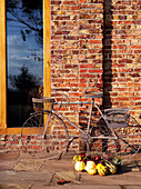 Old fashioned bicycle and vegetables on brick exterior of country home